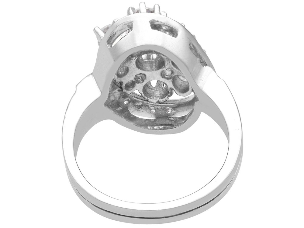 A vintage 1950s 14ct white gold dress ring featuring a multi-diamond cluster and curved accent bands. View VII