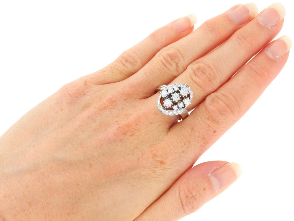 A vintage 1950s 14ct white gold dress ring featuring a multi-diamond cluster and curved accent bands. View X