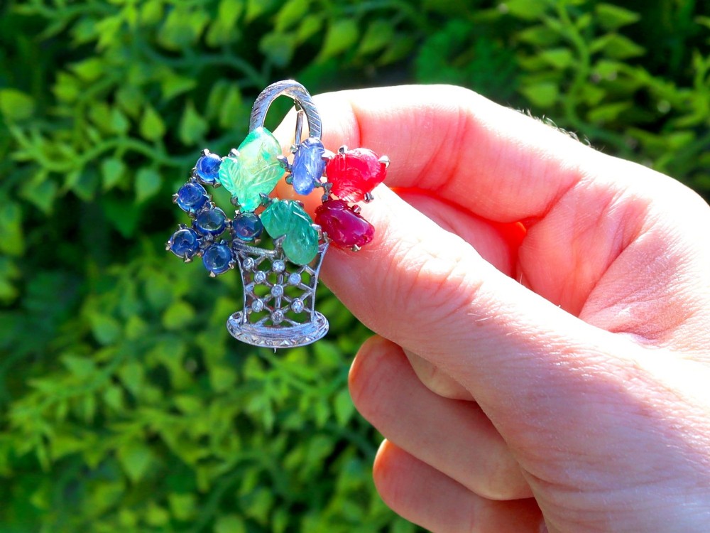 An 18ct white gold Tutti Frutti basket brooch featuring carved emeralds, rubies, sapphire cabochons, and small diamonds. View II