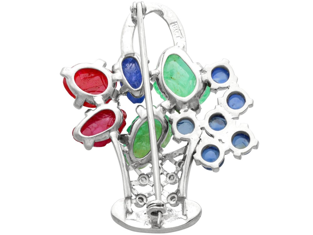 An 18ct white gold Tutti Frutti basket brooch featuring carved emeralds, rubies, sapphire cabochons, and small diamonds. View IX