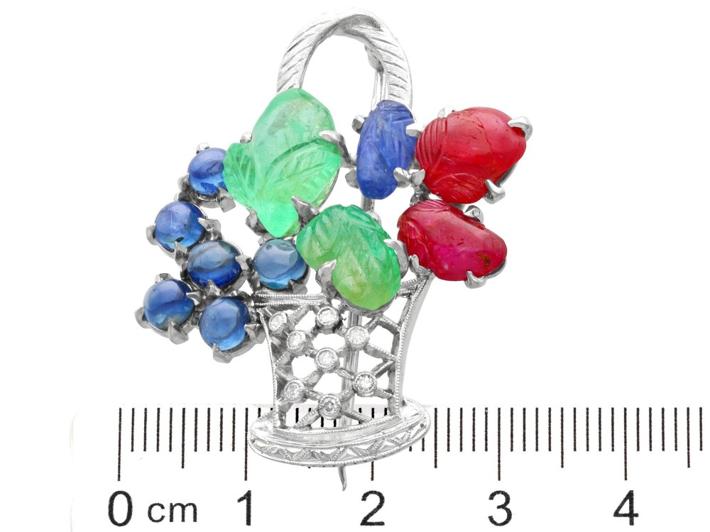An 18ct white gold Tutti Frutti basket brooch featuring carved emeralds, rubies, sapphire cabochons, and small diamonds. View XI