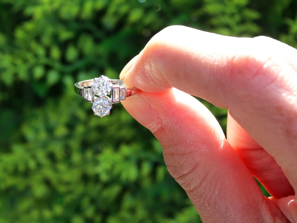 An Art Deco 18ct white gold two-stone diamond ring with stepped baguette cut diamond shoulders. View II