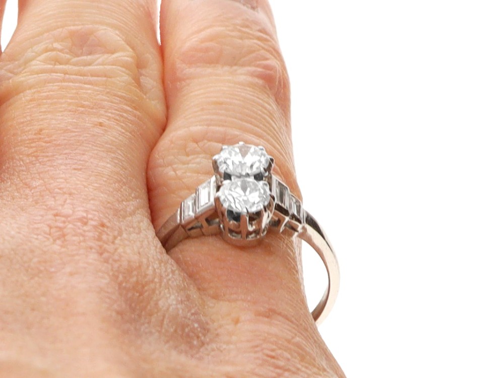 An Art Deco 18ct white gold two-stone diamond ring with stepped baguette cut diamond shoulders. View X