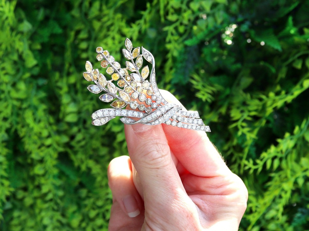 An Art Deco diamond brooch designed as a stylized flower spray with yellow and white diamonds mounted in palladium with a safety chain. View II