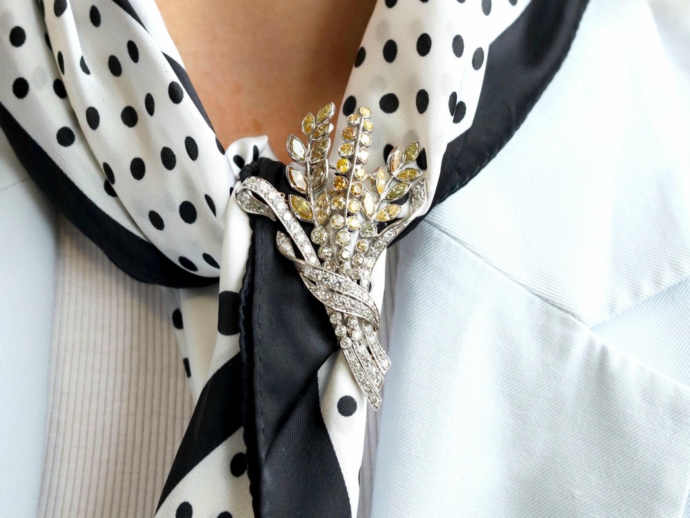 An Art Deco diamond brooch designed as a stylized flower spray with yellow and white diamonds mounted in palladium with a safety chain. View IV