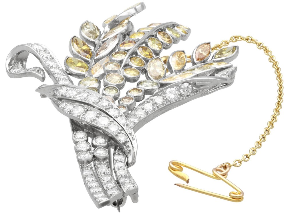 An Art Deco diamond brooch designed as a stylized flower spray with yellow and white diamonds mounted in palladium with a safety chain. View VI
