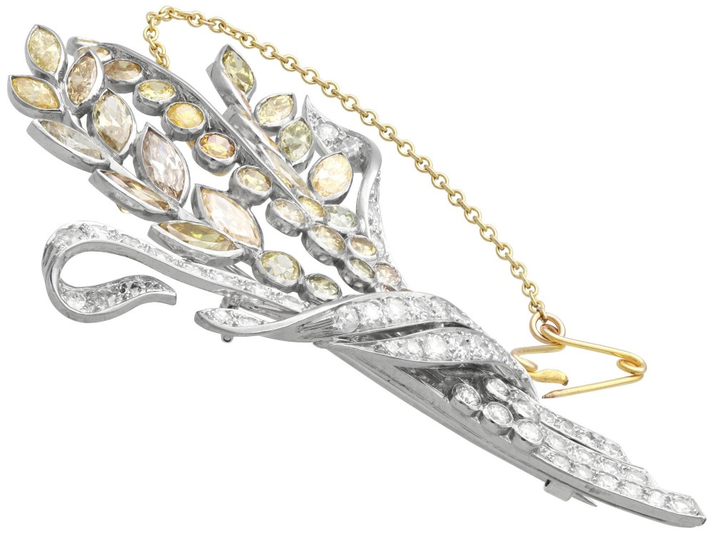 An Art Deco diamond brooch designed as a stylized flower spray with yellow and white diamonds mounted in palladium with a safety chain. View VII