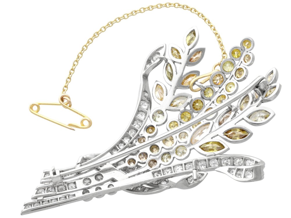 An Art Deco diamond brooch designed as a stylized flower spray with yellow and white diamonds mounted in palladium with a safety chain. View VIII