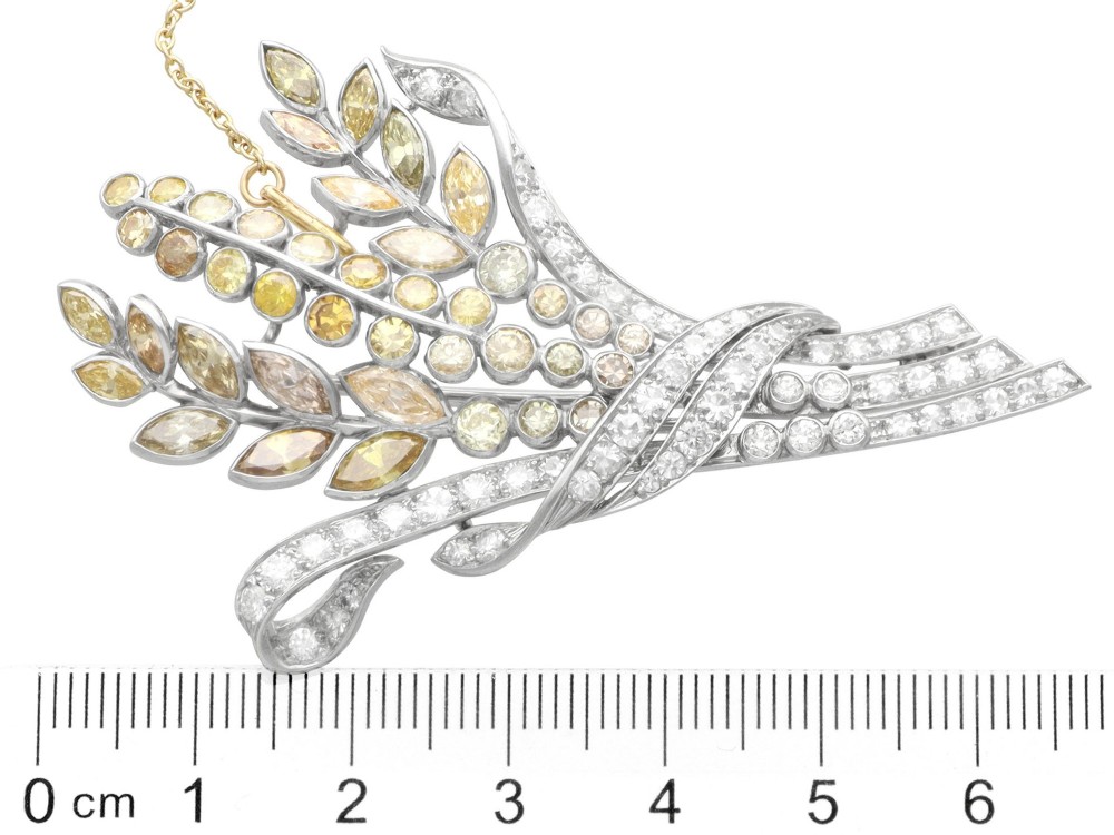 An Art Deco diamond brooch designed as a stylized flower spray with yellow and white diamonds mounted in palladium with a safety chain. View X
