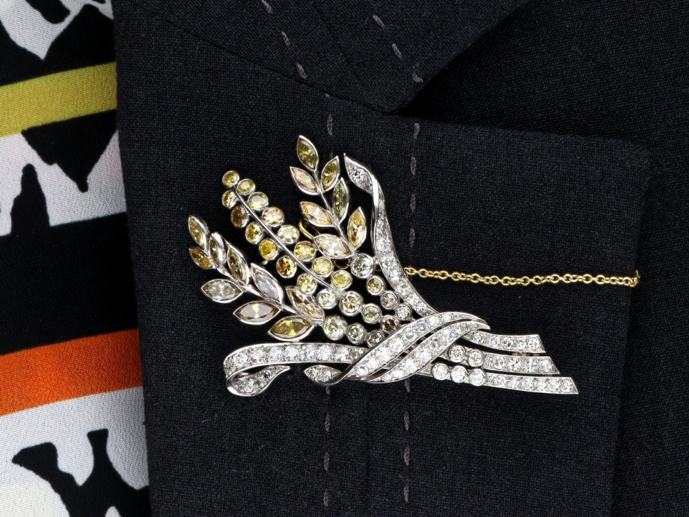 An Art Deco diamond brooch designed as a stylized flower spray with yellow and white diamonds mounted in palladium with a safety chain. View XII