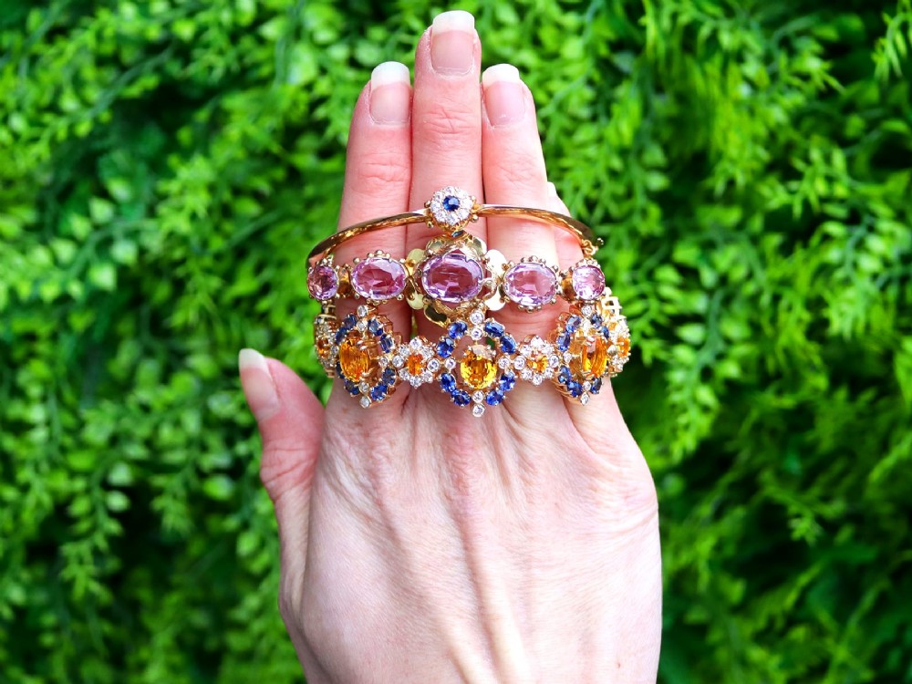 An antique 15ct yellow gold hinged bangle featuring a central circular cluster of diamonds around a dark blue sapphire. View III