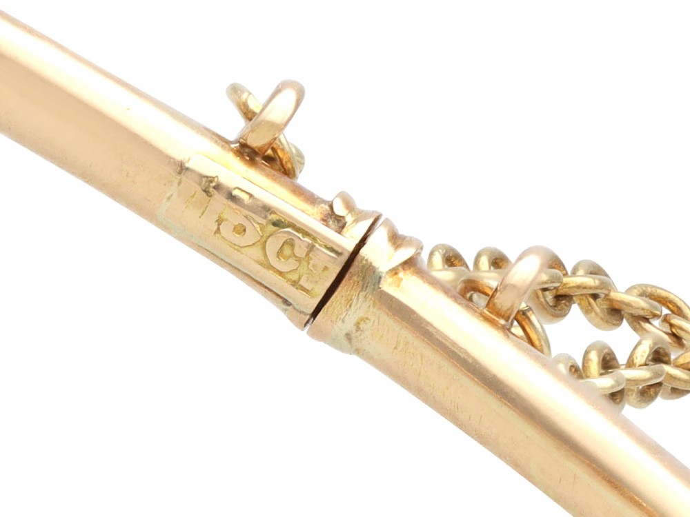 An antique 15ct yellow gold hinged bangle featuring a central circular cluster of diamonds around a dark blue sapphire. View XII