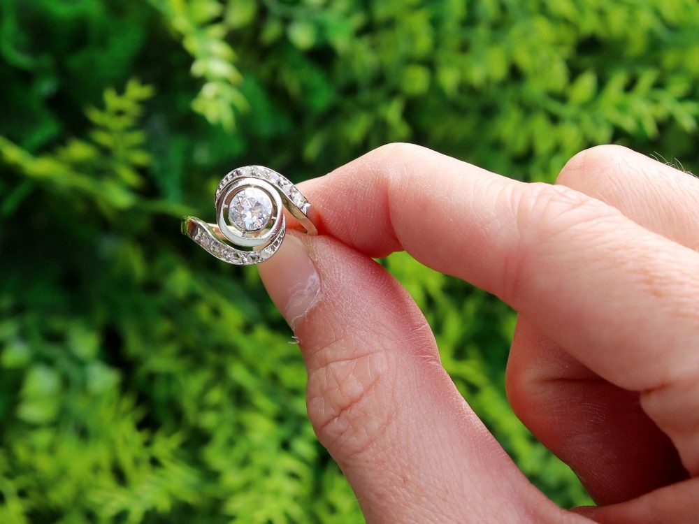 An antique 18ct yellow gold twist ring featuring a central round diamond set within a swooping platinum accent band set with smaller diamonds. View II