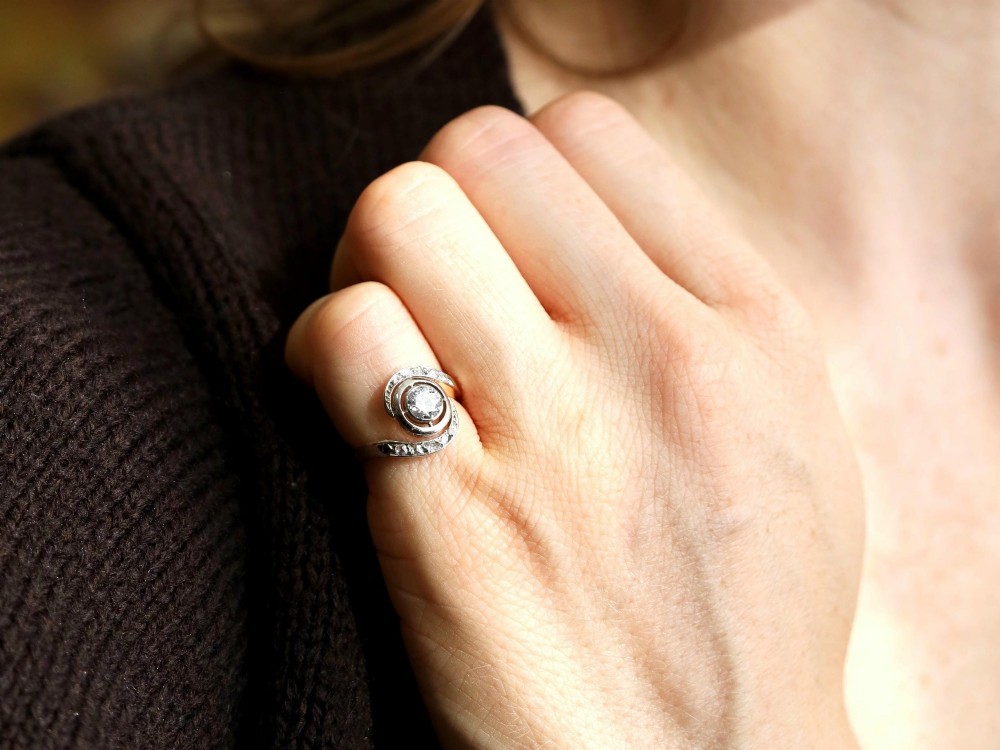 An antique 18ct yellow gold twist ring featuring a central round diamond set within a swooping platinum accent band set with smaller diamonds. View III