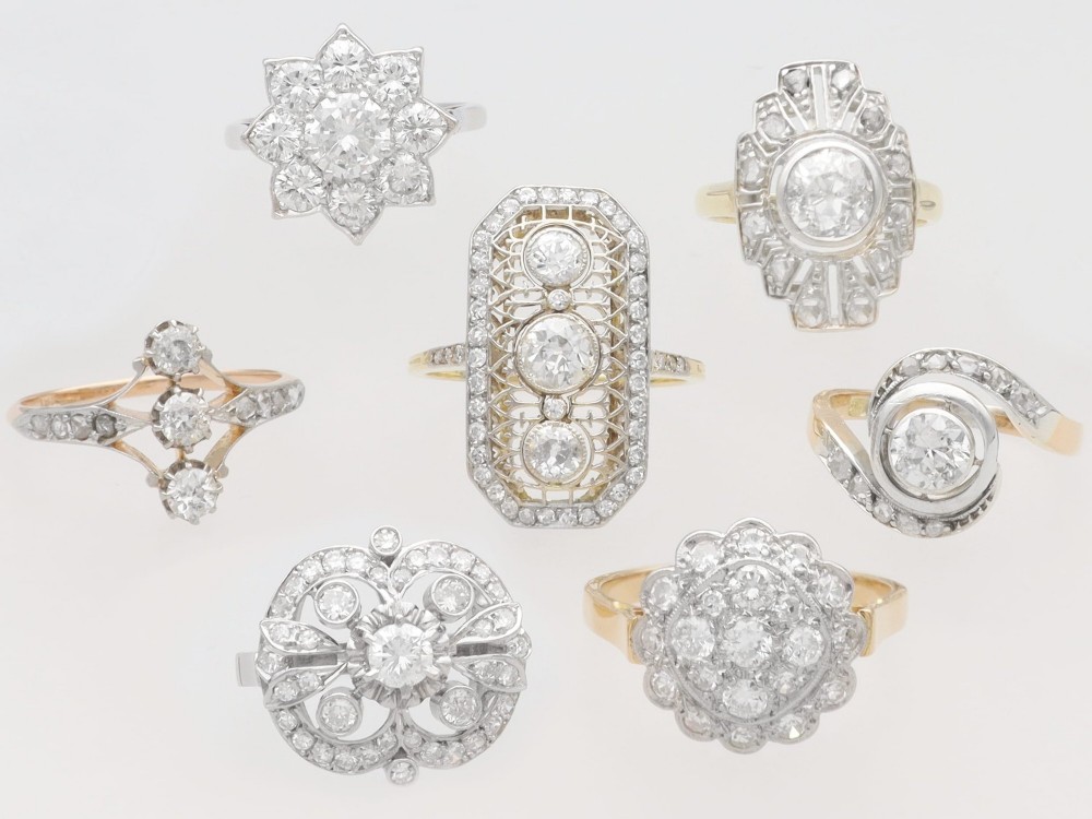 An antique 18ct yellow gold twist ring featuring a central round diamond set within a swooping platinum accent band set with smaller diamonds. View VI