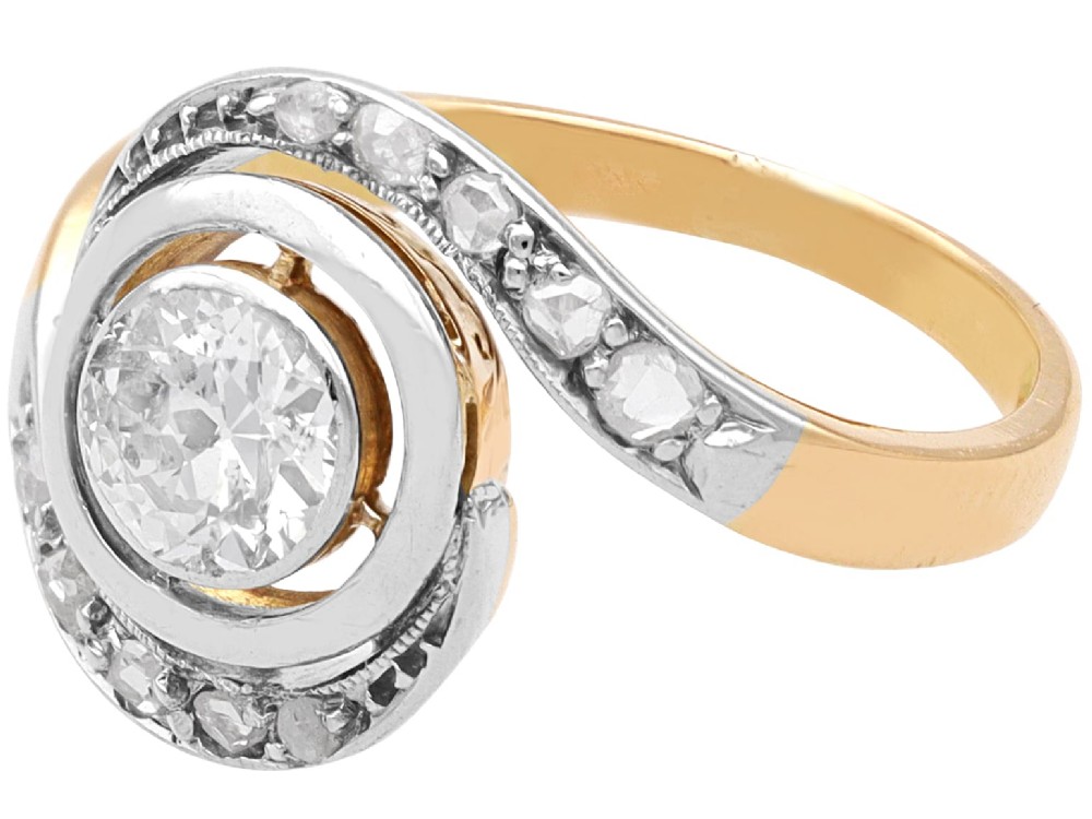 An antique 18ct yellow gold twist ring featuring a central round diamond set within a swooping platinum accent band set with smaller diamonds. View VIII