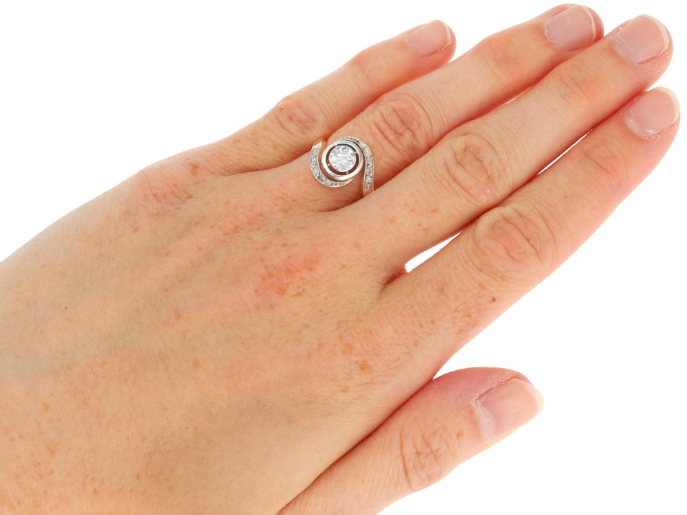 An antique 18ct yellow gold twist ring featuring a central round diamond set within a swooping platinum accent band set with smaller diamonds. View XII