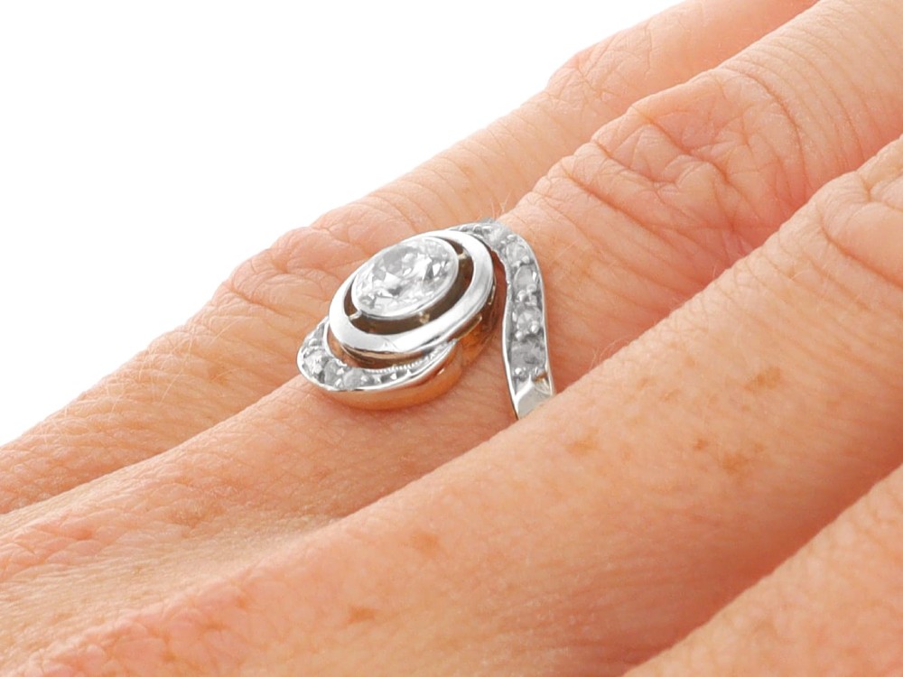 An antique 18ct yellow gold twist ring featuring a central round diamond set within a swooping platinum accent band set with smaller diamonds. View XIII
