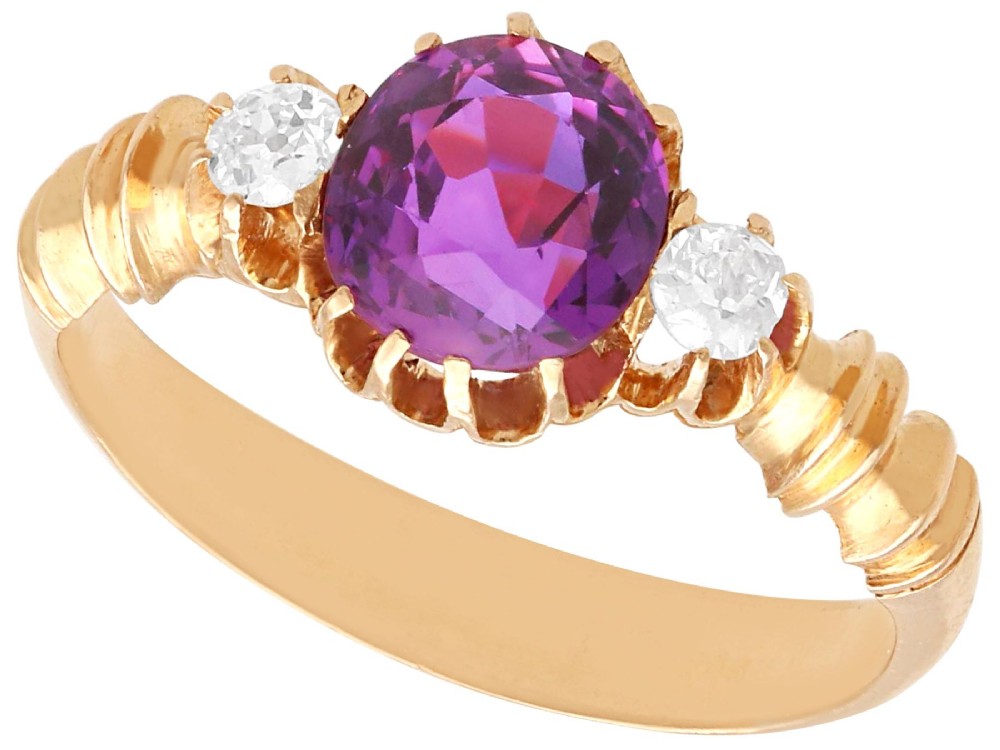 A Victorian 15ct rose gold trilogy ring set with a central purple sapphire flanked by two diamonds on carved shoulders.