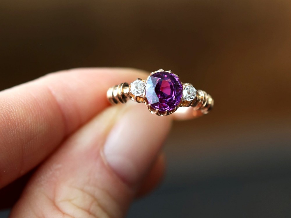 A Victorian 15ct rose gold trilogy ring set with a central purple sapphire flanked by two diamonds on carved shoulders. View III