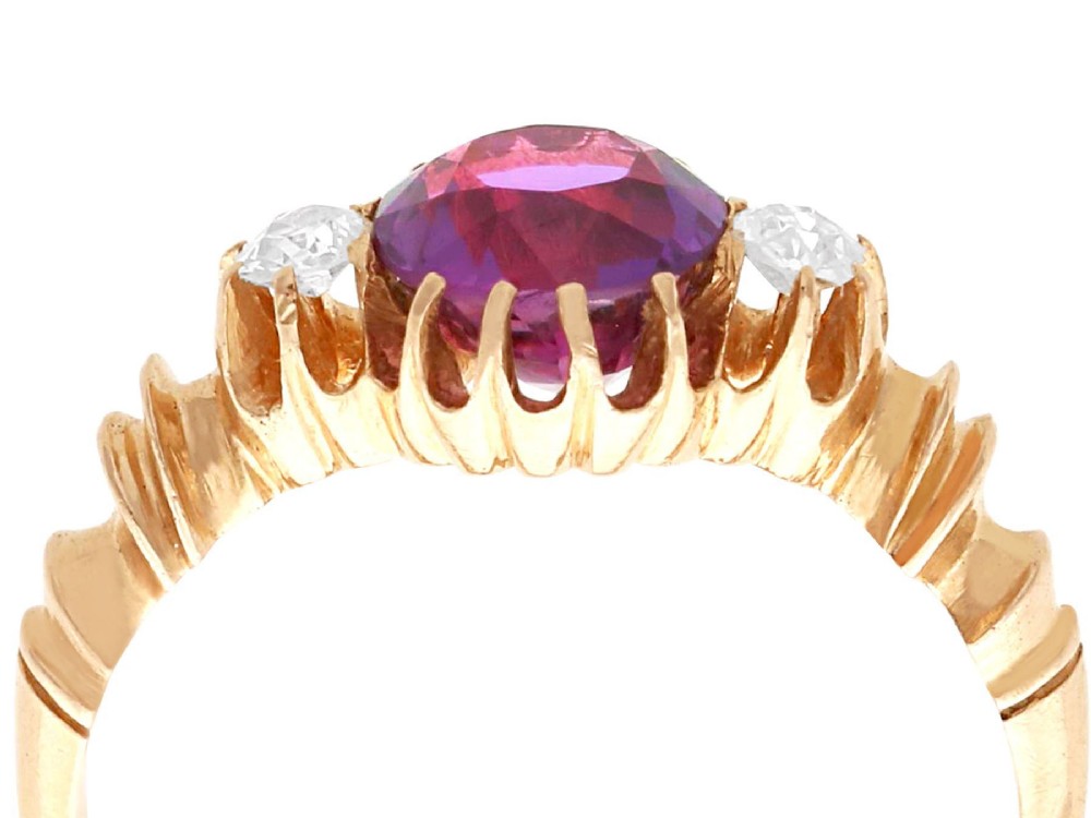 A Victorian 15ct rose gold trilogy ring set with a central purple sapphire flanked by two diamonds on carved shoulders. View VII