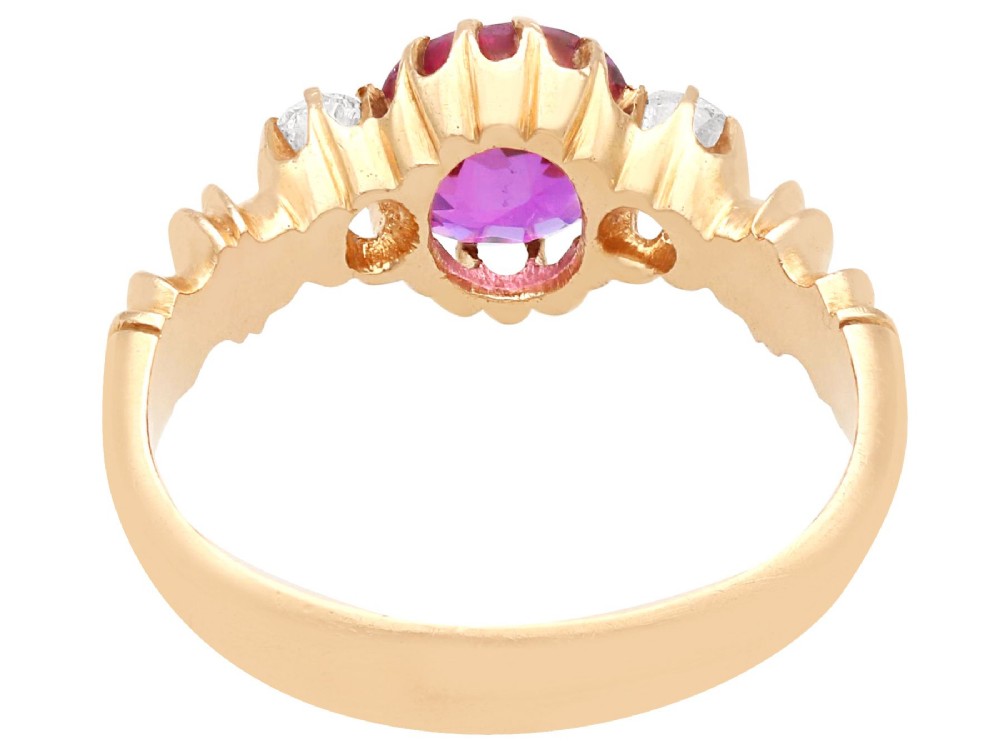 A Victorian 15ct rose gold trilogy ring set with a central purple sapphire flanked by two diamonds on carved shoulders. View IX