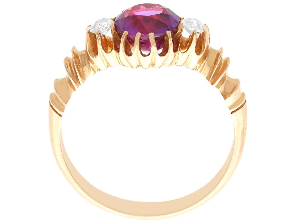 A Victorian 15ct rose gold trilogy ring set with a central purple sapphire flanked by two diamonds on carved shoulders. View X