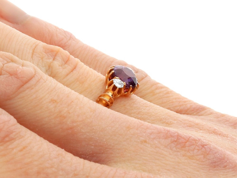 A Victorian 15ct rose gold trilogy ring set with a central purple sapphire flanked by two diamonds on carved shoulders. View XI