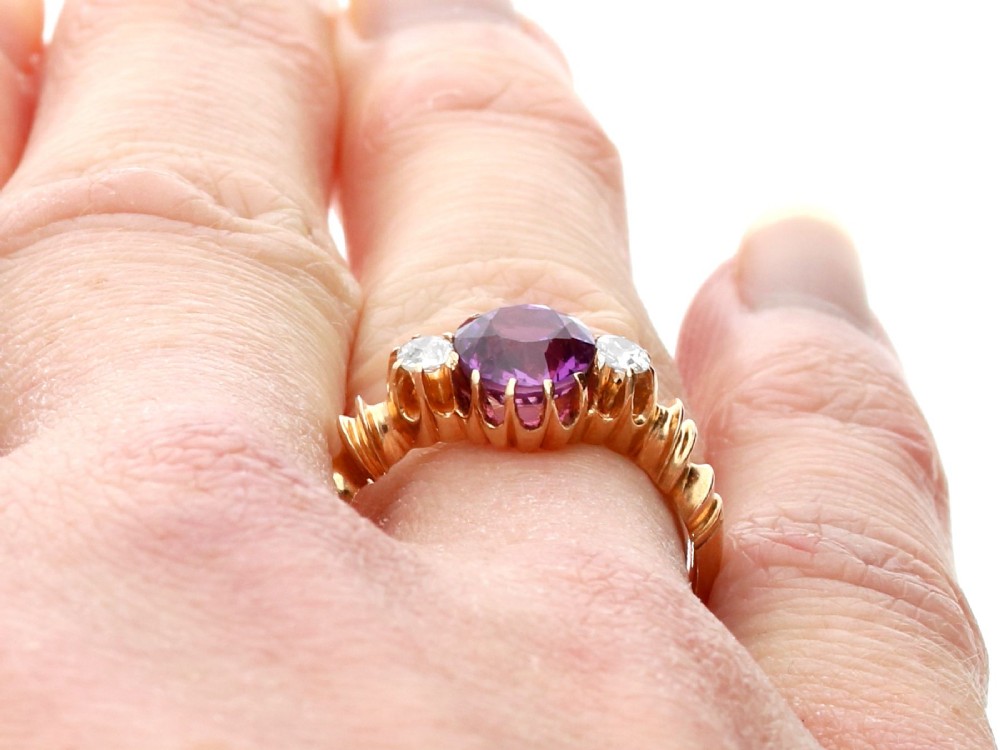 A Victorian 15ct rose gold trilogy ring set with a central purple sapphire flanked by two diamonds on carved shoulders. View XII