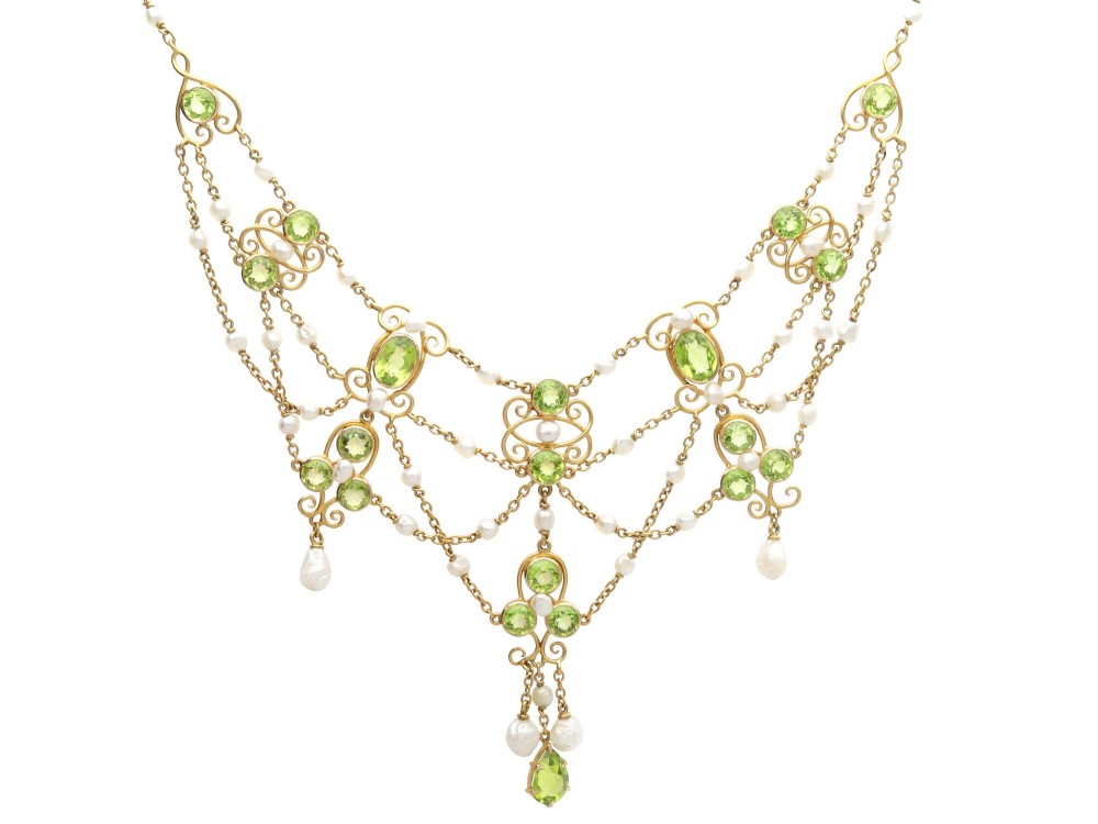 An 18ct yellow gold Belle Epoque festoon necklace featuring faceted green peridots, intricate scrollwork, and suspended natural pearl drops.