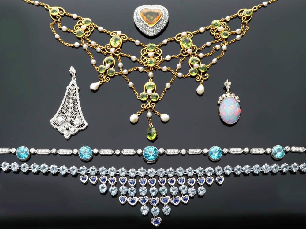 An 18ct yellow gold Belle Epoque festoon necklace featuring faceted green peridots, intricate scrollwork, and suspended natural pearl drops. View VI