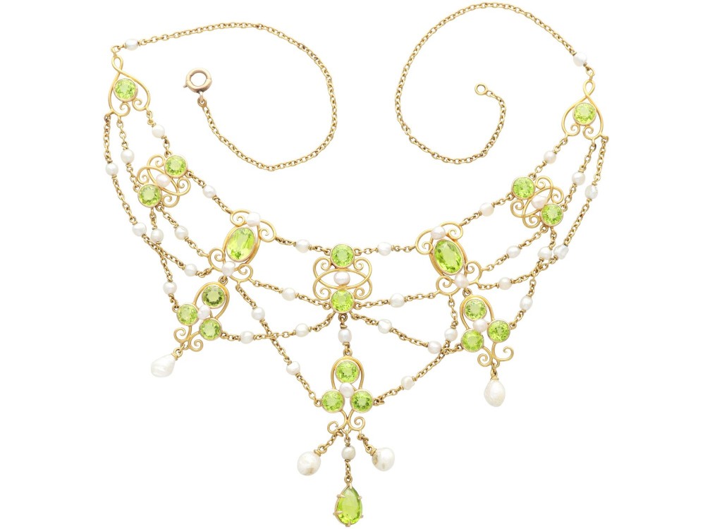 An 18ct yellow gold Belle Epoque festoon necklace featuring faceted green peridots, intricate scrollwork, and suspended natural pearl drops. View VII
