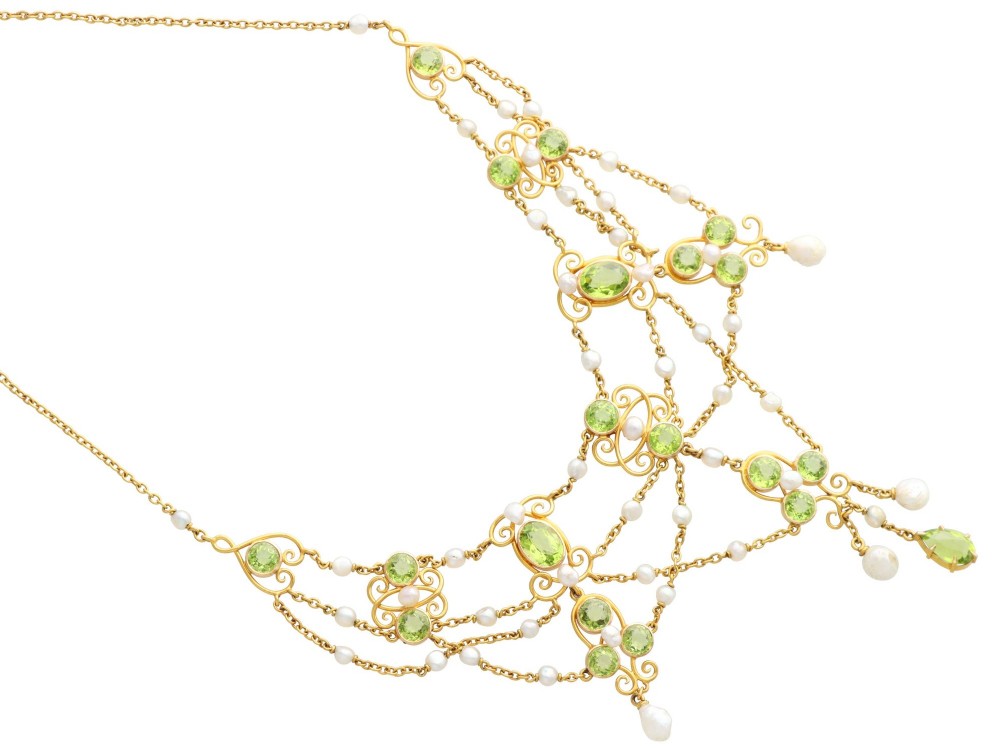 An 18ct yellow gold Belle Epoque festoon necklace featuring faceted green peridots, intricate scrollwork, and suspended natural pearl drops. View IX