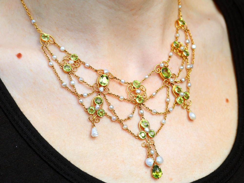 An 18ct yellow gold Belle Epoque festoon necklace featuring faceted green peridots, intricate scrollwork, and suspended natural pearl drops. View XIII