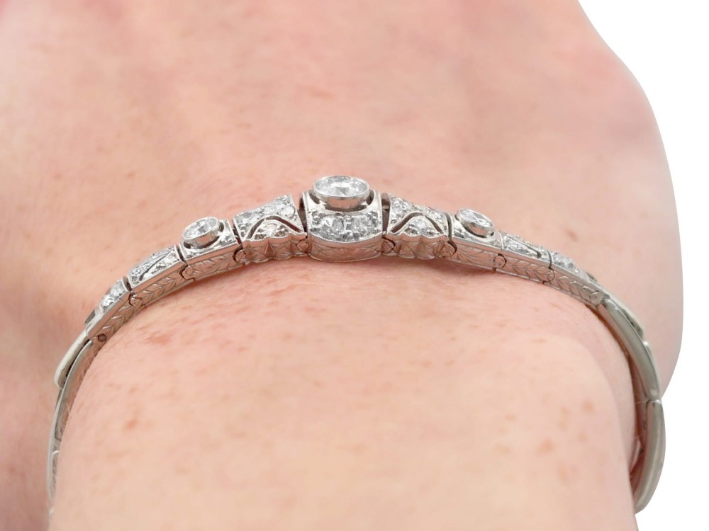 An Art Deco 18ct white gold bracelet featuring articulated geometric panels set with diamonds and finished with millegrain edging. View XI
