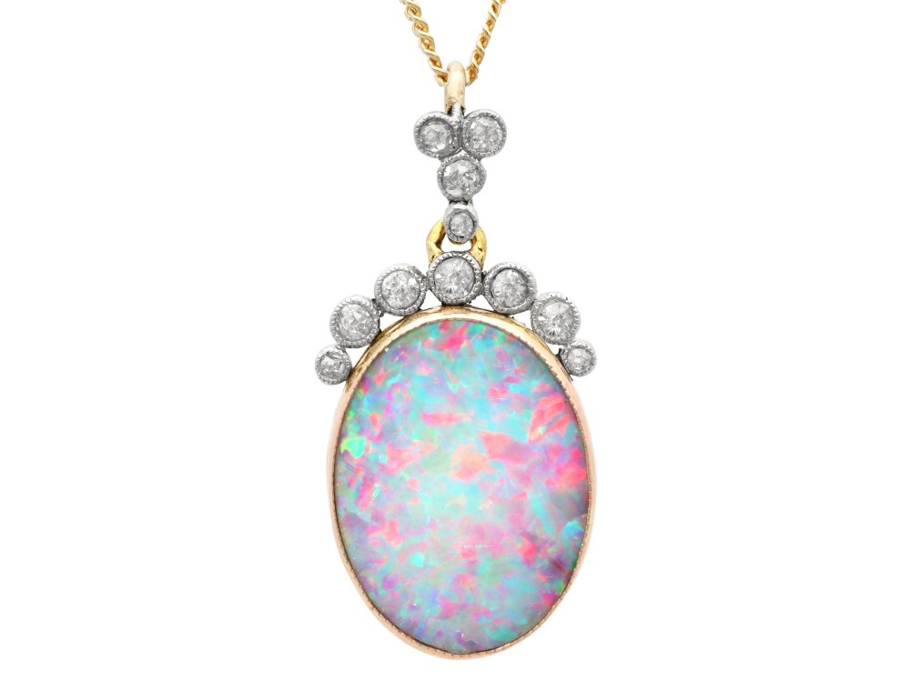 An Edwardian 9ct yellow gold pendant featuring an oval cabochon opal surmounted by millegrain-set diamonds.