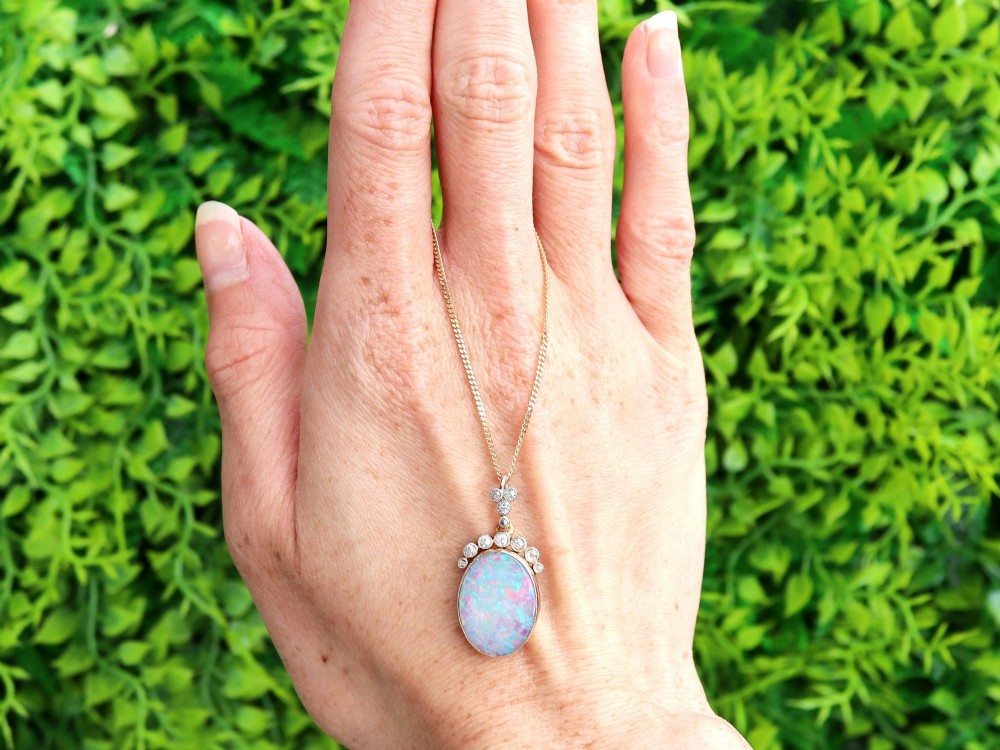 An Edwardian 9ct yellow gold pendant featuring an oval cabochon opal surmounted by millegrain-set diamonds. View II