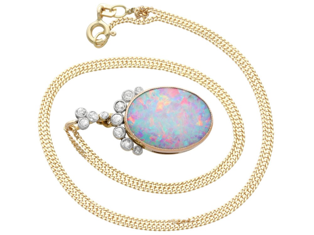 An Edwardian 9ct yellow gold pendant featuring an oval cabochon opal surmounted by millegrain-set diamonds. View IX