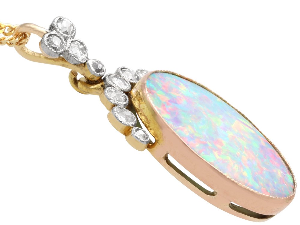 An Edwardian 9ct yellow gold pendant featuring an oval cabochon opal surmounted by millegrain-set diamonds. View X