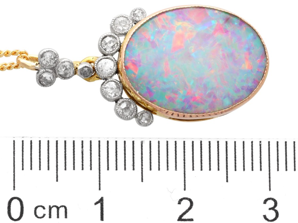 An Edwardian 9ct yellow gold pendant featuring an oval cabochon opal surmounted by millegrain-set diamonds. View XII