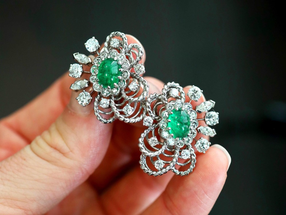 A pair of platinum and palladium clip earrings featuring oval central emeralds surrounded by brilliant-cut diamonds and rope-twist metalwork. View III