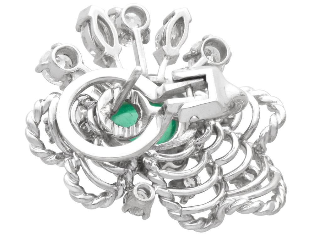 A pair of platinum and palladium clip earrings featuring oval central emeralds surrounded by brilliant-cut diamonds and rope-twist metalwork. View VII