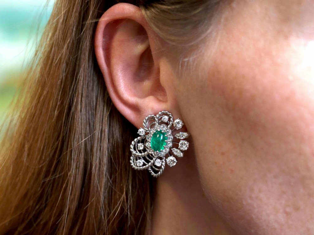 A pair of platinum and palladium clip earrings featuring oval central emeralds surrounded by brilliant-cut diamonds and rope-twist metalwork. View XI