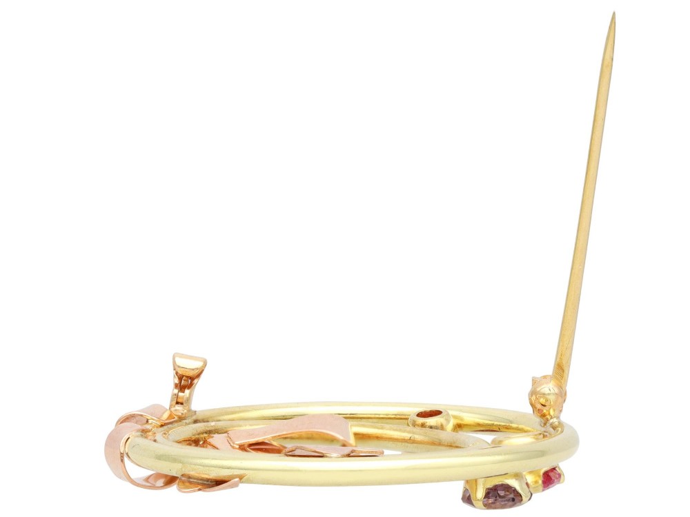 A circular two-tone gold brooch featuring yellow gold concentric rings set with three pink spinels and decorated with a rose gold bow. View XII