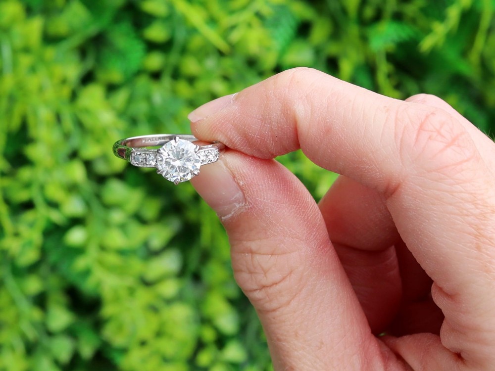 A platinum solitaire ring set with a central round diamond and smaller diamond accents on the shoulders. View II