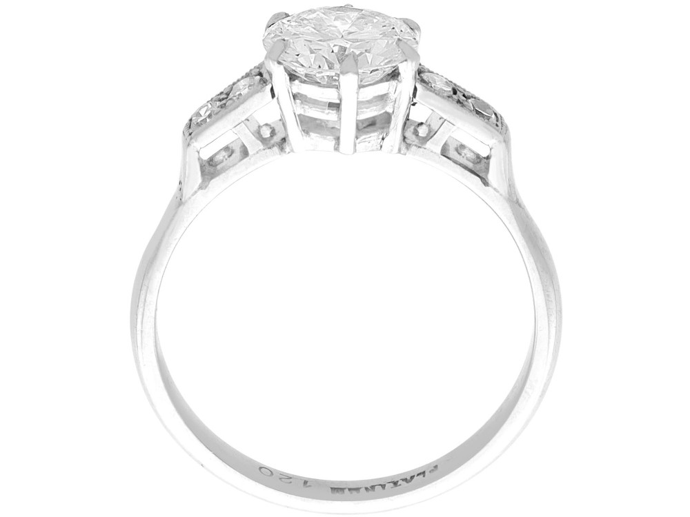 A platinum solitaire ring set with a central round diamond and smaller diamond accents on the shoulders. View VIII