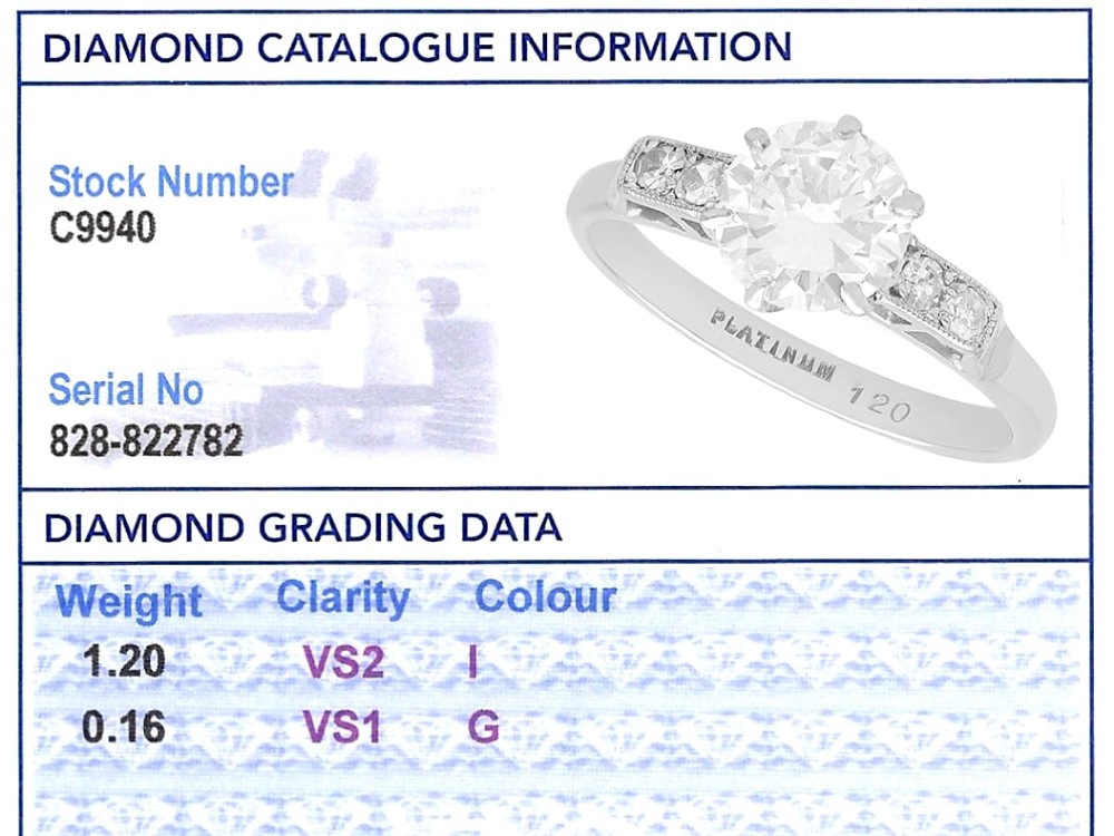 A platinum solitaire ring set with a central round diamond and smaller diamond accents on the shoulders. View XII