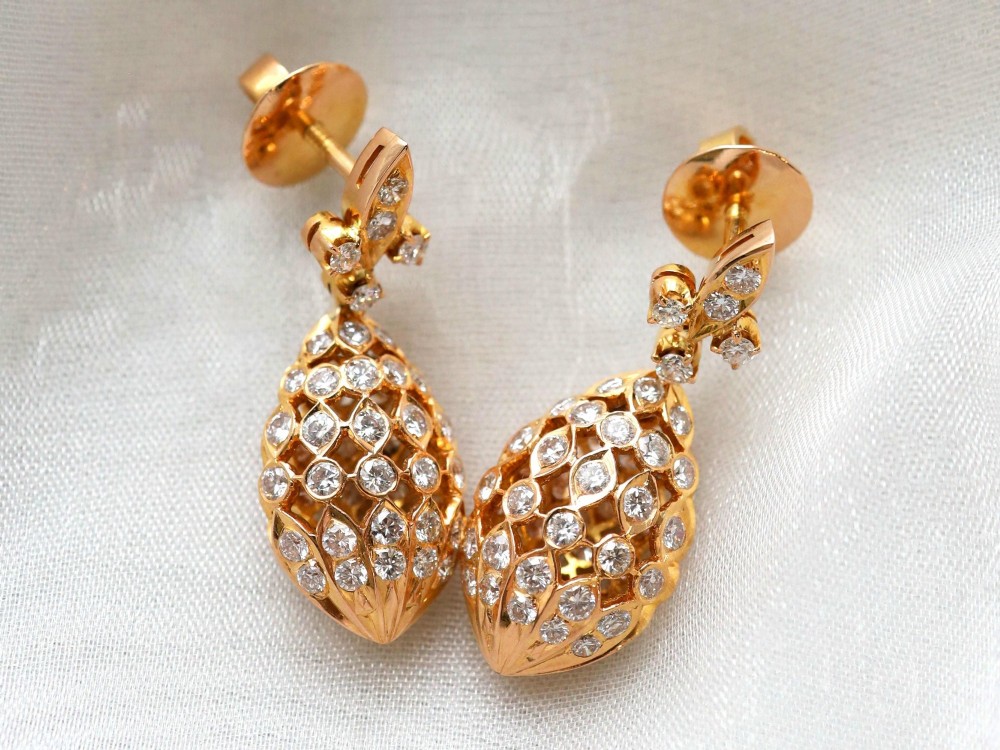 A pair of 18ct yellow gold drop earrings featuring fleur-de-lis surmounts above openwork teardrop cages set with round diamonds. View IV