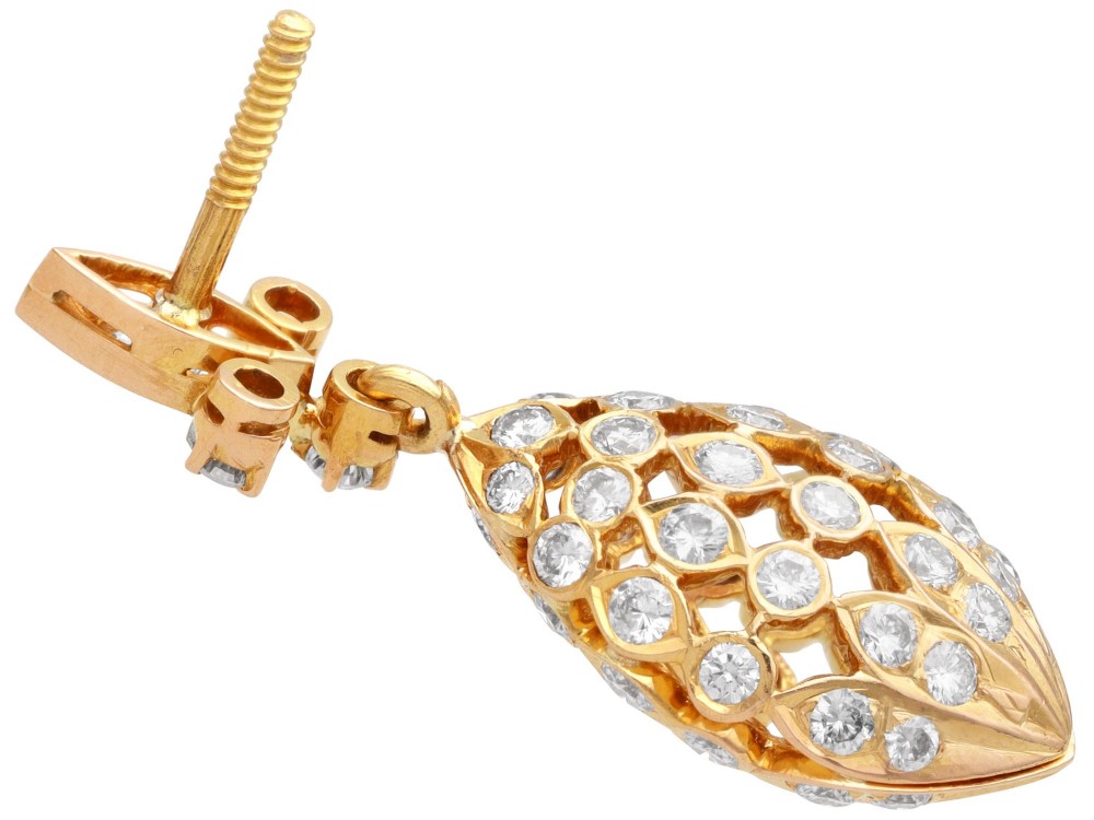 A pair of 18ct yellow gold drop earrings featuring fleur-de-lis surmounts above openwork teardrop cages set with round diamonds. View IX