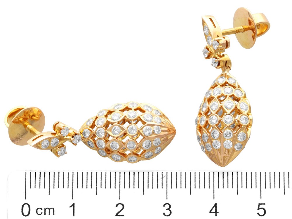 A pair of 18ct yellow gold drop earrings featuring fleur-de-lis surmounts above openwork teardrop cages set with round diamonds. View X